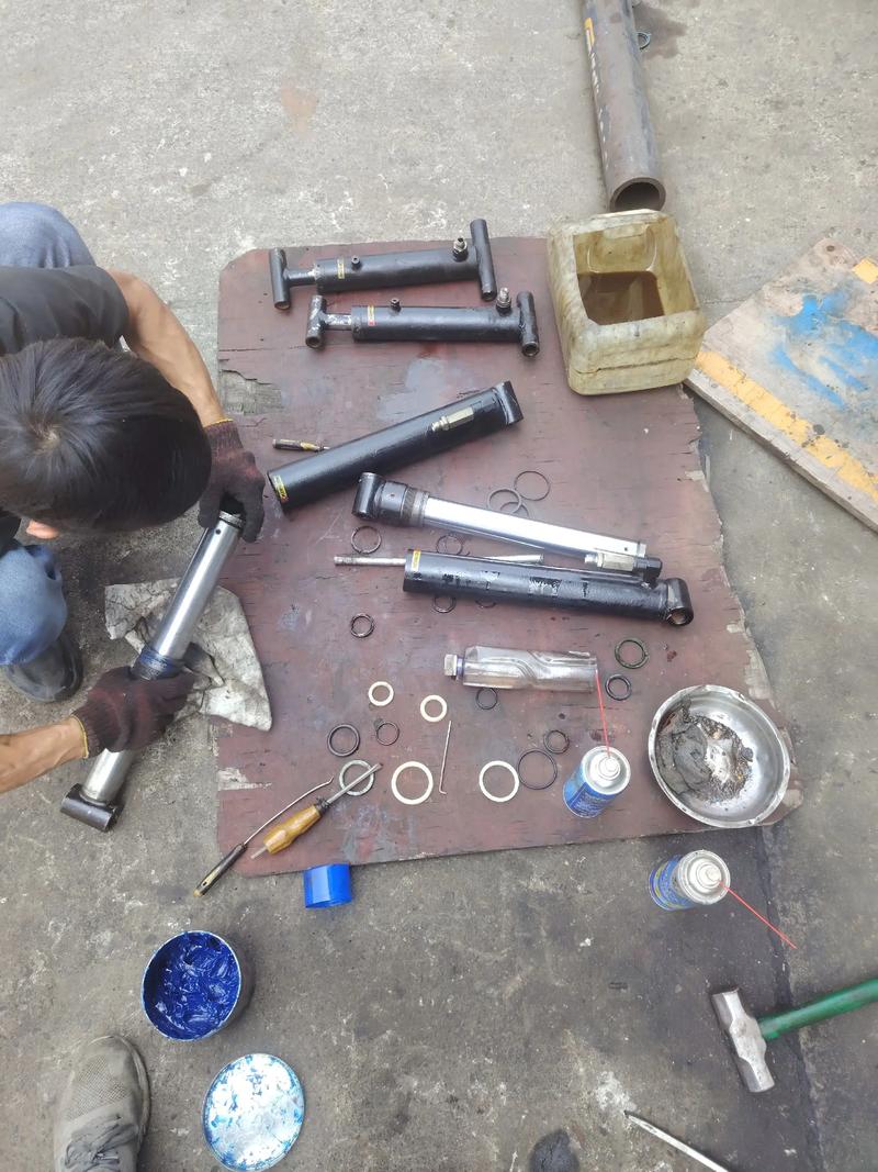 Technician hand-stoning an epoxy repair flush on a hydraulic cylinder rod